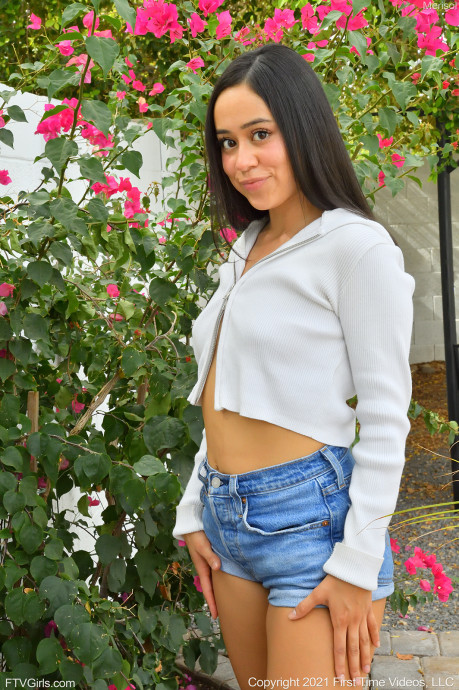 teen pornstar merisol ftv is non nude wearing a sexy blue denim shorts and white long sleeve shirt while standing near some plants with flowers in White Cotton Panties
