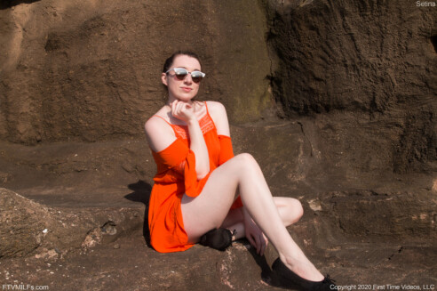 milf pornstar Setina FTV is sitting on the rocks wearing an orange sexy dress and black shoes and shades in Cliffside Cutie