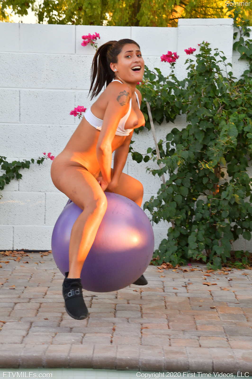 mature Sommer FTV is sitting on a gym ball as she bounces from it while naked showing her tits near a pool