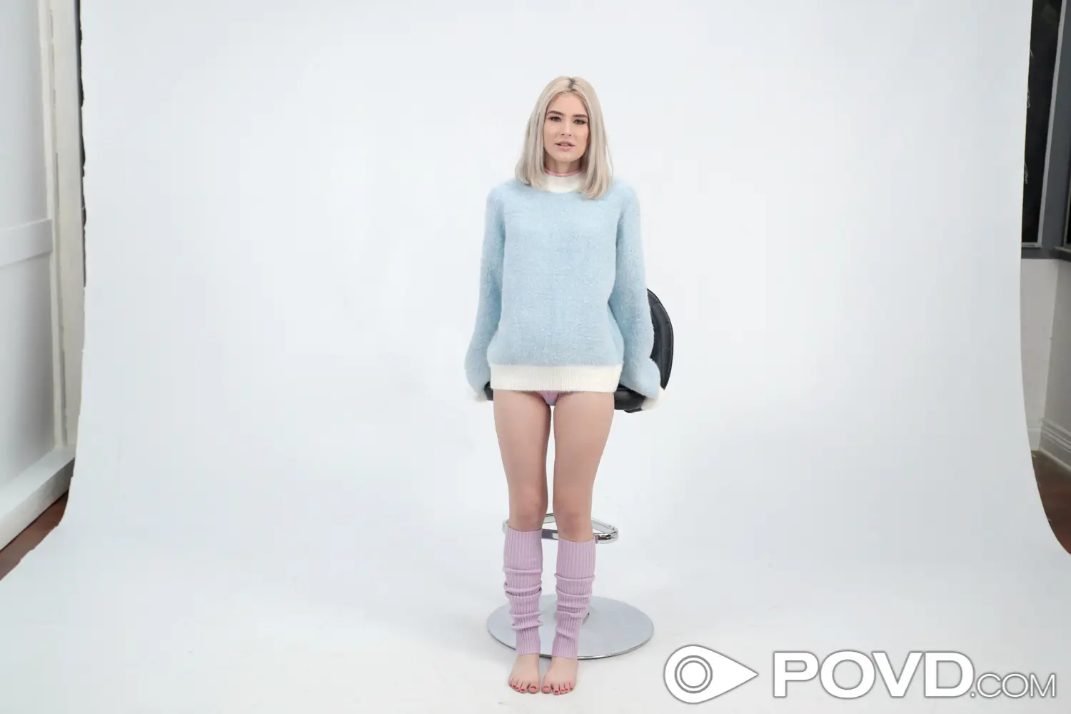 a non nude teen pornstar Jessie Saint is standing near a chair while wearing a long light blue long sleeves in Seducing the Photographer